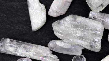 chiaro kunzite mucchio su gioiello pietre struttura su nero pietra sfondo. in movimento giusto senza soluzione di continuità ciclo continuo sfondo. video