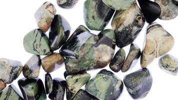 Kambaba jasper heap jewel stones texture on white light background. Moving right seamless loop backdrop. video