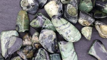Kambaba jasper heap up jewel stones texture on black stone background. Moving right seamless loop backdrop. video