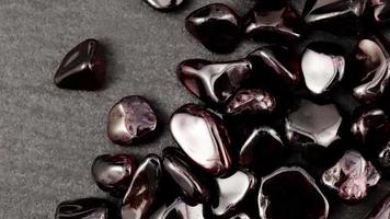 Garnet heap up jewel stones texture on black stone background. Moving right seamless loop backdrop. video