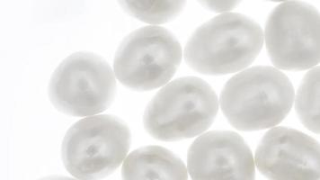 Pearl heap up jewel stones texture on light white isolated background. Moving right seamless loop backdrop. video