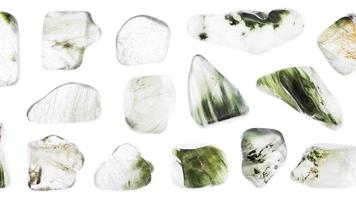 Green rutilated jewel stones set texture on light white isolated background. Macro closeup. Moving right seamless loop backdrop. video