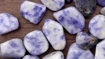 Sodalite heap up jewel stones texture on brown varnished wood background. Moving right seamless loop backdrop. video