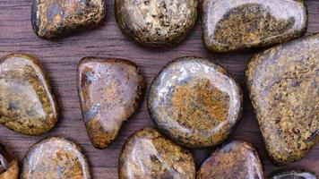 Bronzite heap up jewel stones on brown varnished wood texture. Moving right seamless loop backdrop. video