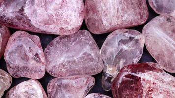 Strawberry quartz heap jewel stones texture on black background. Moving right seamless loop backdrop. video