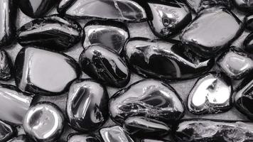Black tourmaline gemstone heap jewel texture on black stone background. Moving right seamless loop backdrop. video