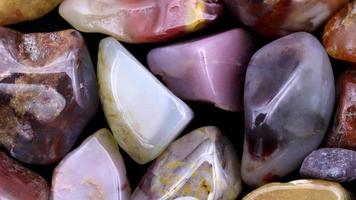 Yanyuan agate heap jewel stones texture on black background. Moving right seamless loop backdrop. video