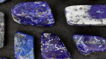 Lapis lazuli rare jewel stones texture on black stone background. Moving right seamless loop backdrop. video