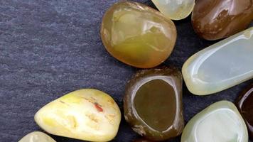 Yellow Agate heap up jewel stones on black stone texture. Moving right seamless loop backdrop. video