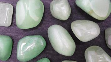 Green Aventurine rare jewel on black stone texture. Moving right seamless loop backdrop. video