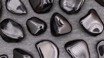 Obsidian rare jewel stones texture on black stone background. Moving right seamless loop backdrop. video