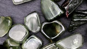 Green rutilated heap up jewel stones texture on black stone background. Moving right seamless loop backdrop. video