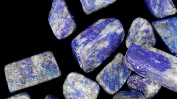 Lapis lazuli heap up jewel stones texture on black background. Moving right seamless loop backdrop. video