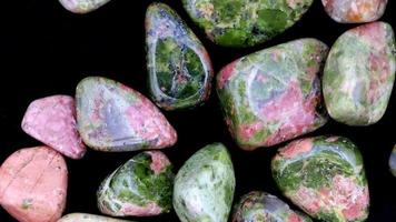 Unakite heap up jewel stones texture on black background. Moving right seamless loop backdrop. video