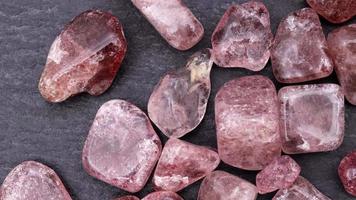 Strawberry quartz heap up jewel stones texture on black stone background. Moving right seamless loop backdrop. video