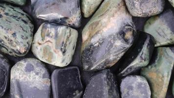 Kambaba jasper heap jewel stones texture on black background. Moving right seamless loop backdrop. video