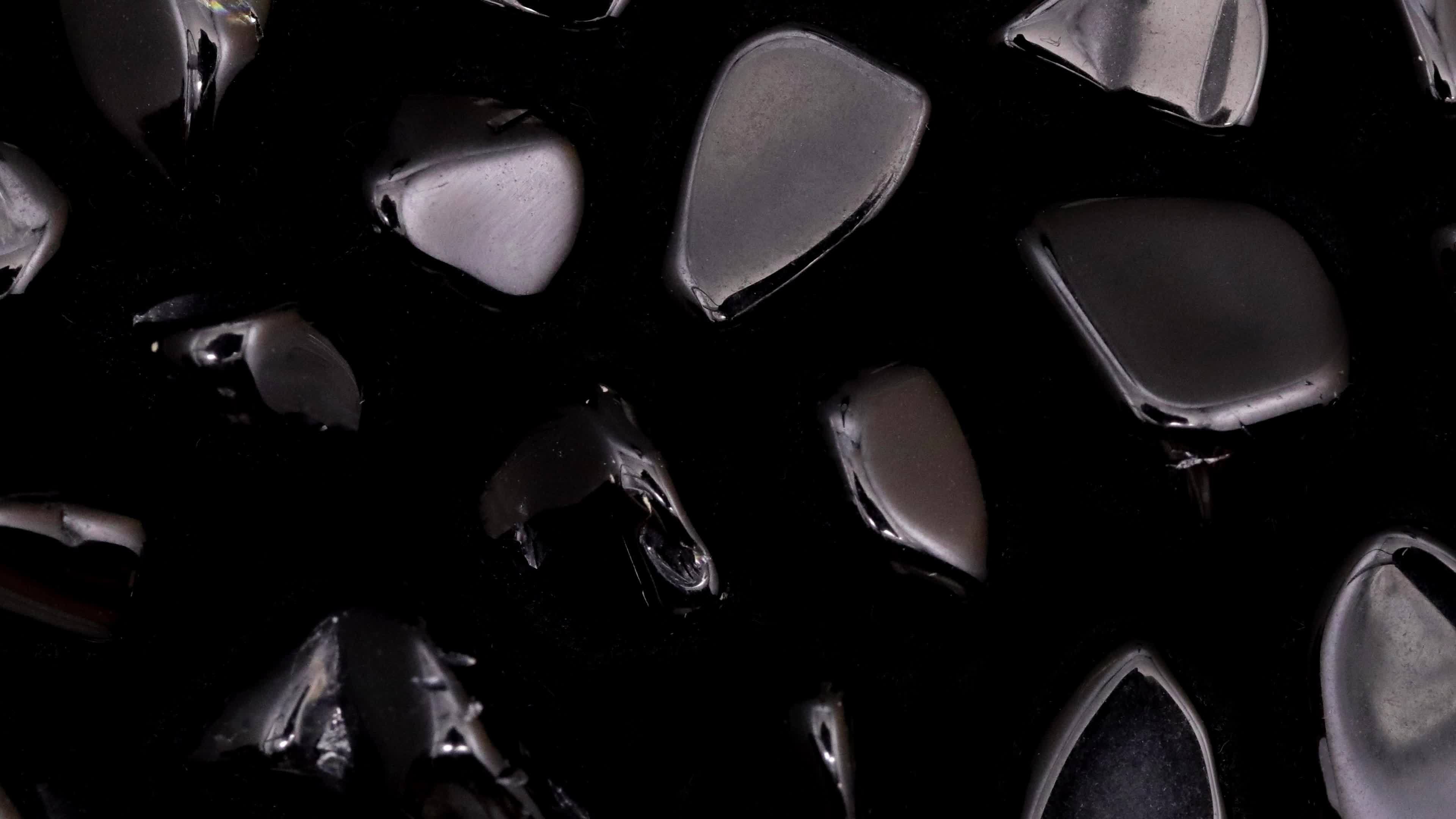 Obsidian rare jewel stones texture on black background. Moving right