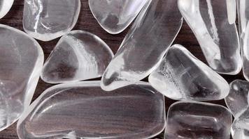 Clear quartz jewel heap on varnished brown wood background. Moving right seamless loop backdrop. video