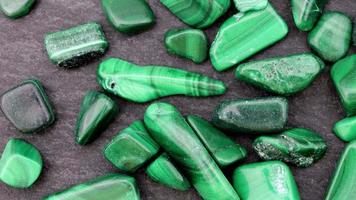 Malachite heap up jewel stones texture on black stone background. Moving right seamless loop backdrop. video