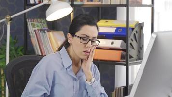 mujer de negocios aburrida en la oficina. la mujer de negocios que trabaja en el aburrimiento trabaja en la computadora. video