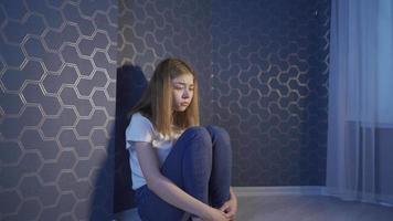 niña deprimida, infeliz y llena de reproches. la joven que está sola en casa está triste y se derrumba contra la pared.