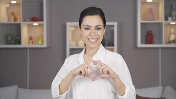 Loving woman looking at camera making heart. Happy woman looking at camera and smiling making heart. video