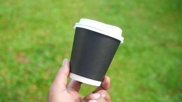 Adult hand holding a paper disposable coffee cup outside video