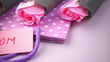 rosas rosadas, una bolsa de compras y una nota para mamá
