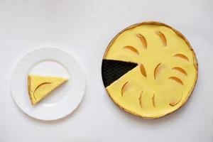 yellow peach pie with a slice cut off on a white background. photo