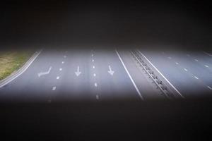 forward and left arrow on the track. White arrow sign painted on black asphalt. Transport background. Three-lane modern asphalt road photo