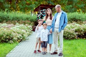 familia caminando en el parque. mamá, papá y 2 hijos. una familia con dos hijos. foto