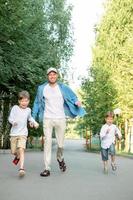 family walking in park. dad and sons are running. Happy dad with children. Dad and 2 sons. photo