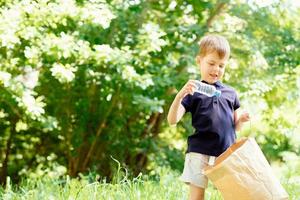 Save environment concept, a little boy collecting garbage and plastic bottles on the beach to dumped into the trash photo