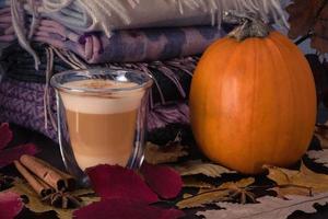 Heat-resistant glass cup with pumpkin latte and ripe pumpkin stand on table photo