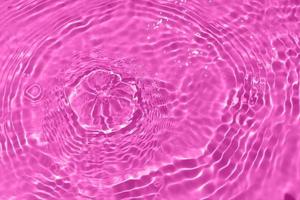 Defocus blurred transparent purple colored clear calm water surface texture with splashes and bubbles. Trendy abstract nature background. Water waves in sunlight with copy space. Watercolor shine photo