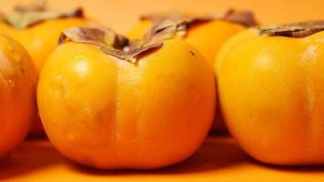 Persimmons close up on orange background