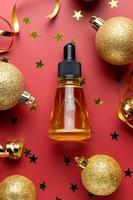 Top view of face essemtial oil with natural ingredients on red gitter background with streamers. New year or christmas gifts of skincare products and cosmetics. photo