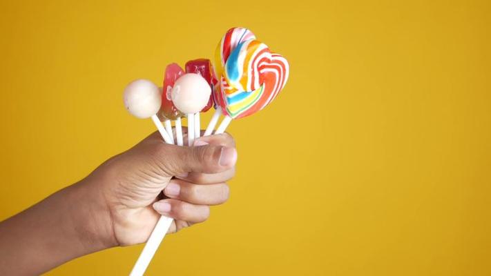 Candy making in the market. Hands move swiftly rolling the molten  multicoloured candy into mouth watering suckers Stock Photo - Alamy