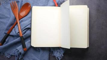 Open pages of a blank notebook in kitchen next to wooden utensils video