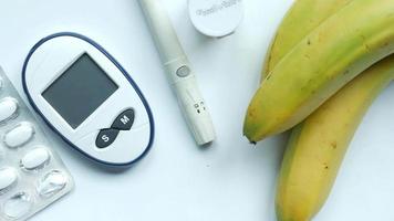 A pill blister, blood monitor, bananas on white surface video