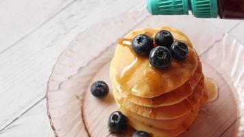 A pile of small pancakes with blueberries and maple syrup video