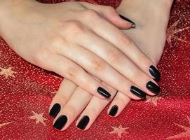 hermosas manos de mujer con manicura negra esmalte de uñas negro. uñas cuidadas con esmalte de uñas negro. foto