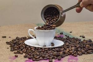 Abstract . Hand pouring coffee beans from coffee pot to cup photo