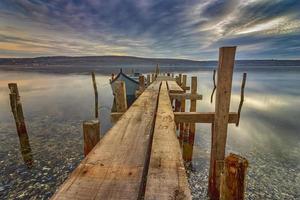 different angle. Exciting long exposure landscape of wooden pier and boat in a lake.Close photo