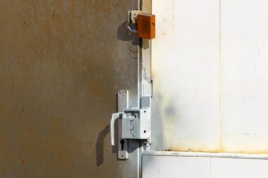 A rusty padlock hangs on a closed gate. photo