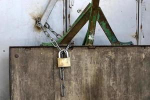 A rusty padlock hangs on a closed gate. photo