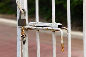 A rusty padlock hangs on a closed gate. photo