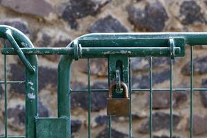 A rusty padlock hangs on a closed gate. photo