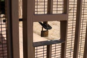 A rusty padlock hangs on a closed gate. photo