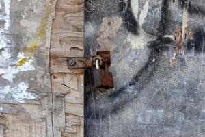 un candado oxidado cuelga de una puerta cerrada. foto